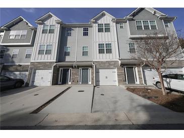 Three-story townhomes featuring attached garages and modern exteriors with gray siding and stone accents at 951 Plaza Park Walk # 50, Kennesaw, GA 30144