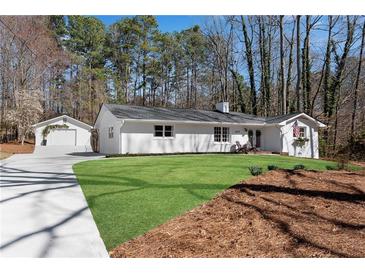 Charming renovated ranch home featuring a lush lawn, painted white brick, detached garage and a welcoming front porch at 5079 Ne Dogwood Hills Dr, Sugar Hill, GA 30518