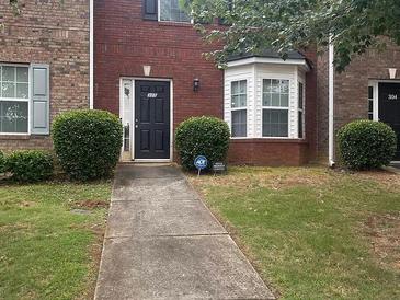 Traditional brick townhouse with a well-manicured lawn and black front door with an ADT security sign at 7712 Autry Cir # 305, Douglasville, GA 30134