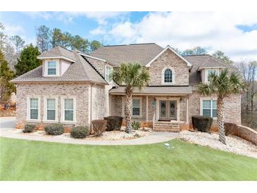Charming two-story brick home featuring a well-manicured lawn and beautiful landscaping, including palm trees at 1227 Castle Point Sw Ct, Conyers, GA 30094