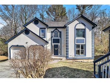 Charming two-story home featuring stucco siding, blue trim, attached garage, and landscaped front yard at 624 Longbow Ct, Stone Mountain, GA 30087