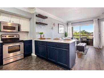 Bright kitchen with stainless steel appliances, tiled backsplash, and center island adjacent to living area at 275 13Th St # Apt 509, Atlanta, GA 30309