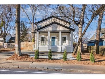 Charming home with a welcoming front porch, white railing, blue front door, and fresh landscaping at 1986 Memorial Se Dr, Atlanta, GA 30317