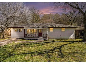 Charming brick home with a cozy front porch, set amidst a lush green lawn and mature trees at 304 Mercer Dr, Jonesboro, GA 30236