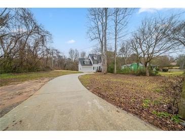 View of the home's exterior, front lawn, long driveway and some winter landscaping at 6112 Shadow Rock Ln, Lithonia, GA 30058