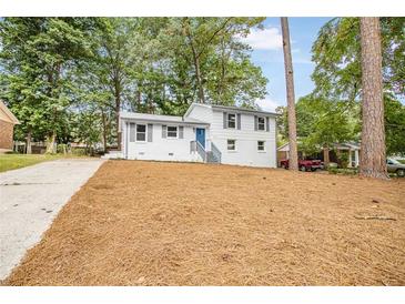 Charming two-story home featuring a white brick facade, blue door, and lovely landscaping at 6539 Hayes Dr, Riverdale, GA 30274