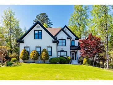 Beautiful two-story home with a lush front lawn, manicured shrubs, and trees at 2660 Portabella Ln, Cumming, GA 30041