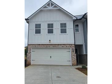 View of garage exterior with brick and white siding; three windows above the two-car garage at 537 Tuskegee St # 48, Mcdonough, GA 30252