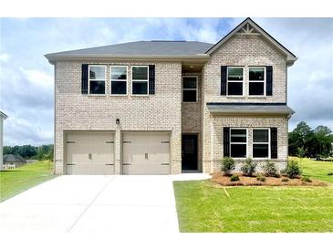Two-story brick home featuring a two-car garage, lush lawn, and dark shutters at 642 Egrets Landing #66, Covington, GA 30014