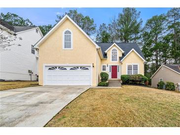Inviting two-story home featuring a two-car garage, a red front door, and a well-manicured lawn at 11853 Harbour Town Pkwy, Fayetteville, GA 30215