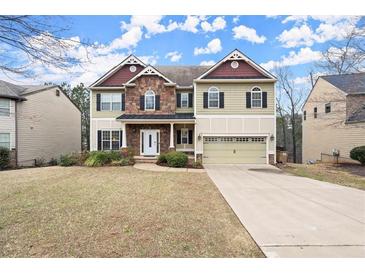 Charming two-story home featuring a stone facade, attached two-car garage, and well-manicured landscaping at 3680 Falling Leaf Ln, Cumming, GA 30041