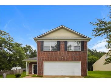 Two story brick home with a two car garage and manicured front lawn underneath a blue sky at 6595 Browns Mill Ferry Dr, Lithonia, GA 30038