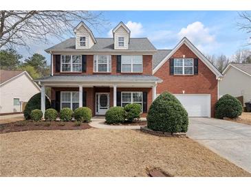 Charming two-story red brick home featuring a welcoming front porch and attached garage at 923 Port West Dr, Auburn, GA 30011