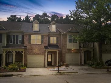Charming brick townhome featuring a two-car garage, covered entry, and dormer windows at 1649 Southgate Mill Dr, Duluth, GA 30096