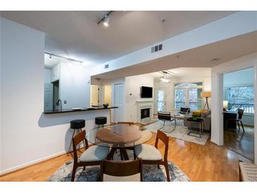 Open-concept living room with hardwood floors, fireplace, and bright windows to balcony at 955 Juniper Ne St # 4229, Atlanta, GA 30309