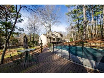 Outdoor pool with a security fence alongside a wooden deck and lush surrounding trees and a backyard at 150 Karina Pl, Canton, GA 30115