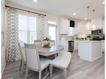 Bright eat-in kitchen features white cabinetry, stainless steel appliances, and a cozy breakfast nook at 1587 Aiden Way # 43, Conyers, GA 30013
