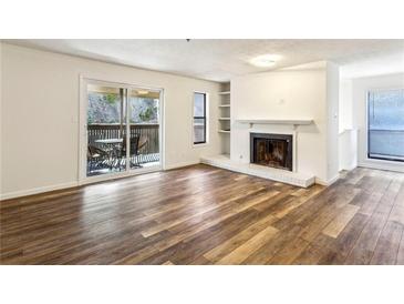 Bright living room featuring wood floors, a fireplace, and sliding glass doors to a deck at 2701 Cumberland Se Ct, Smyrna, GA 30080