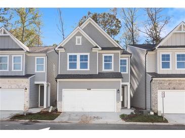 Charming two-story townhome featuring a gray facade, well-manicured lawn, and an attached two-car garage at 686 Smokey Quartz Way, Kennesaw, GA 30144