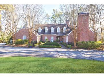 Charming brick home with manicured lawn, fenced entrance, dormer windows, and a prominent chimney at 1762 Nancy Creek Bluff, Atlanta, GA 30305