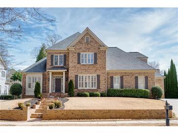 Two-story brick home featuring a manicured lawn, brick stairs, and gray shutters at 5029 Tarry Glen Dr, Suwanee, GA 30024