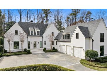 Stunning white home with a circular driveway, manicured landscaping, and an attached three-car garage at 100 Tuxedo Nw Ter, Atlanta, GA 30342