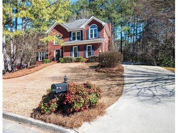 Beautiful two-story red brick home featuring a manicured lawn and a long driveway at 1394 Meadow Springs Dr, Lilburn, GA 30047