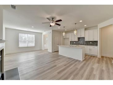 Spacious open concept living room with ceiling fan and kitchen with island at 2761 Sandy Rd, Conyers, GA 30013