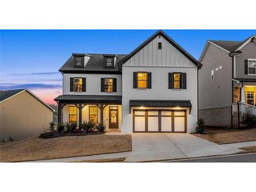 Charming two-story home with a modern white exterior, black trim, covered porch, and an attached two-car garage at 1590 Branthaven Ln, Auburn, GA 30011