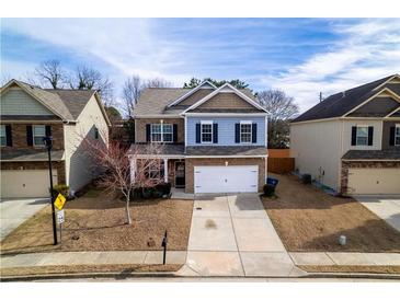 Charming two-story home features blue accents, a two-car garage, and well-maintained landscaping at 1390 Napa Valley Sw Dr, Lawrenceville, GA 30045