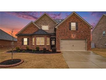 Charming brick home with a manicured lawn, complemented by a two car garage and stone architectural features at 182 Broder Farms Dr, Stockbridge, GA 30281