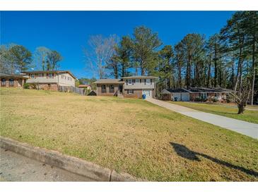 Split-level home with a well-manicured lawn and mature trees at 8904 Creekwood Ct, Riverdale, GA 30274
