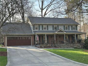 Charming home featuring a welcoming front porch, attached garage, and well-manicured lawn at 1911 Olde Village Run, Dunwoody, GA 30338