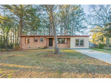 Charming single-story home with brick facade, large windows, and mature trees on a sunny day at 546 W Sherwood Dr, Riverdale, GA 30274