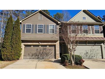 Traditional two-story townhome featuring a two-car garage, brick accents, and neutral toned siding at 115 Sunset Ln, Woodstock, GA 30189