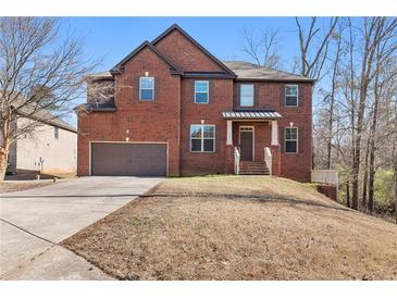 Two-story brick home featuring an attached garage and a well-manicured front yard on a sunny day at 3313 Alhambra Cir, Hampton, GA 30228