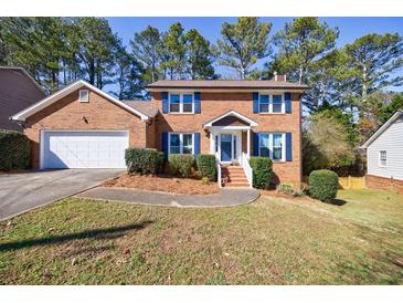 Charming two-story brick home with blue shutters, manicured landscaping, and attached two-car garage at 6507 Bennington Dr, Tucker, GA 30084