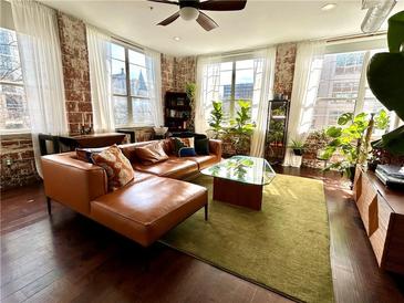 Bright living room with hardwood floors, exposed brick, and modern furniture at 800 Peachtree Ne St # 8415, Atlanta, GA 30308