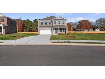 Two-story brick home featuring an attached two-car garage, well-manicured lawn and freshly poured concrete driveway at 108 Dalston Cv, Stockbridge, GA 30281