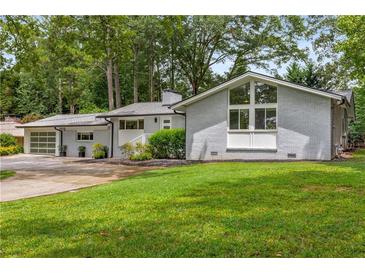 Charming, gray painted brick home with a well-manicured lawn and a large window accent at 3306 Briarcliff Ne Rd, Atlanta, GA 30345