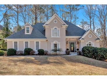 Charming home featuring a stone facade, arched windows, mature trees and a well manicured lawn at 4990 Sawgrass Nw Pl, Acworth, GA 30102