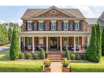 Beautiful two-story brick home featuring a large porch, well-manicured lawn, and professionally landscaped garden at 8025 Georgetown Cir, Suwanee, GA 30024