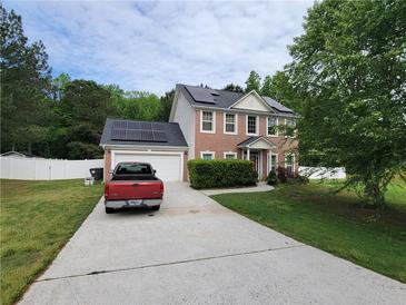 Two-story brick home featuring solar panels, a long driveway, and a well-maintained front yard at 12947 Dunand Blvd, Hampton, GA 30228