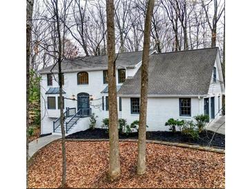 Charming two-story home features a white painted brick facade, black mulch, and a manicured front yard in a wooded setting at 2414 Cedar Wood Ct, Marietta, GA 30068