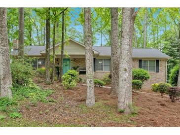 Charming single-story brick home with a well-maintained yard and a front porch surrounded by mature trees at 8980 Country Club Dr, Douglasville, GA 30134