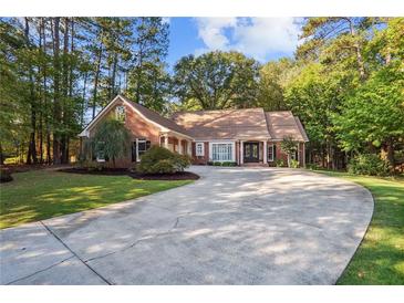 Charming brick home with a circular driveway surrounded by lush landscaping and mature trees at 8900 River Trace Dr, Johns Creek, GA 30097