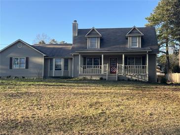 Charming two-story home featuring a cozy front porch and a well-maintained yard on a sunny day at 7977 Woods Ln, Jonesboro, GA 30236