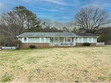 Charming single story home with light green siding, brick accents and a well manicured front lawn at 2056 Merle Se Dr, Conyers, GA 30013