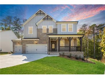 Beautiful two-story home with a brick and gray siding, a front porch with dark wood posts, and a well-manicured lawn at 2460 Hidden Creek Rd, Kennesaw, GA 30152