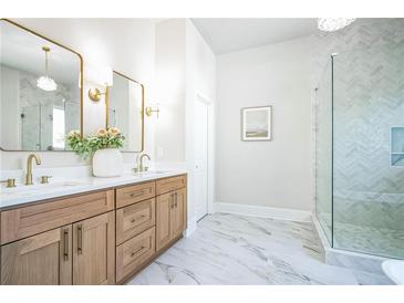 Bright bathroom features double sinks, wood cabinets, modern fixtures, and glass enclosed shower with decorative tile at 1826 Terry Mill Se Rd, Atlanta, GA 30316